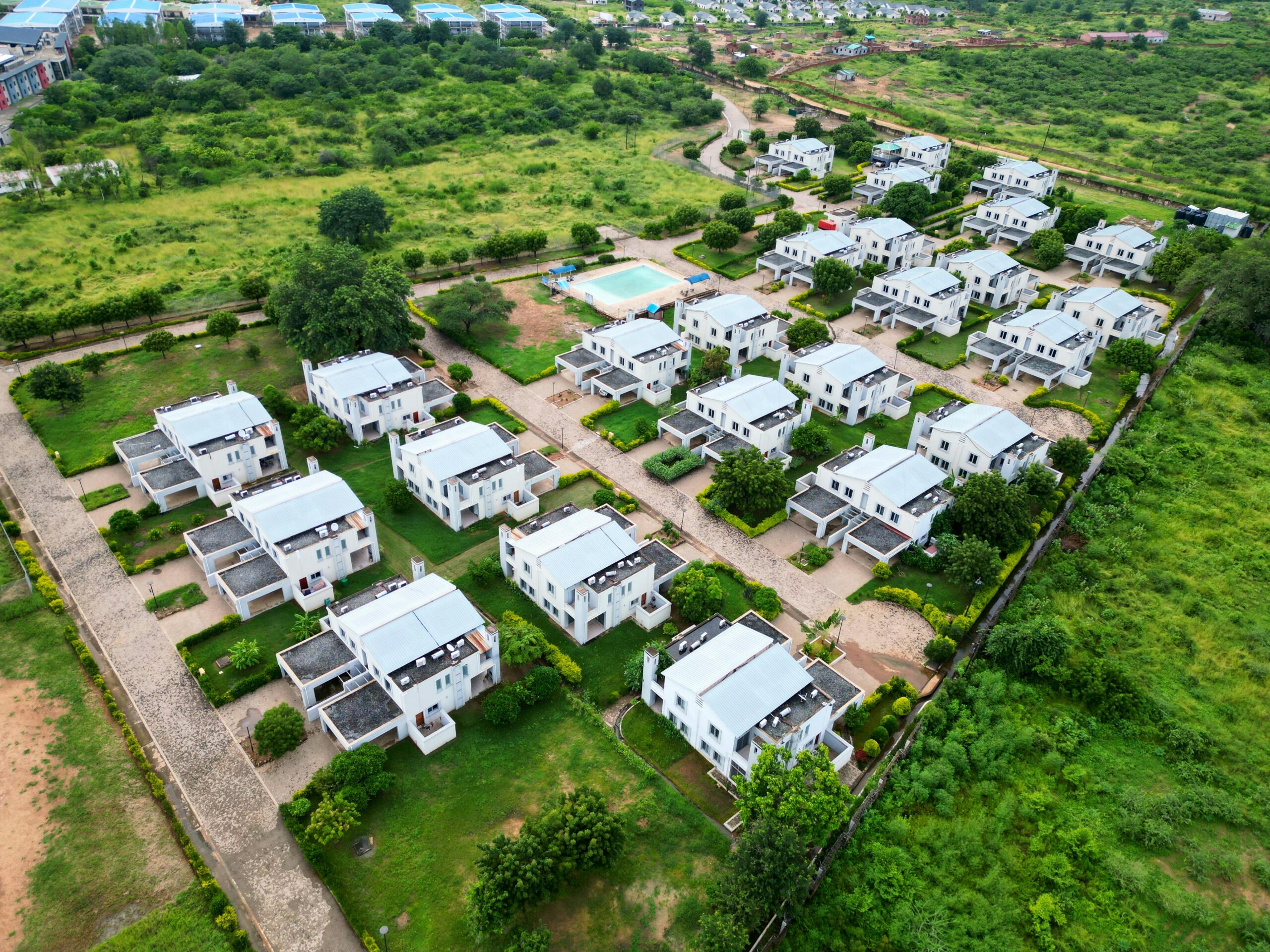 Aerial view of a modern residential neighborhood with white houses and green lawns.