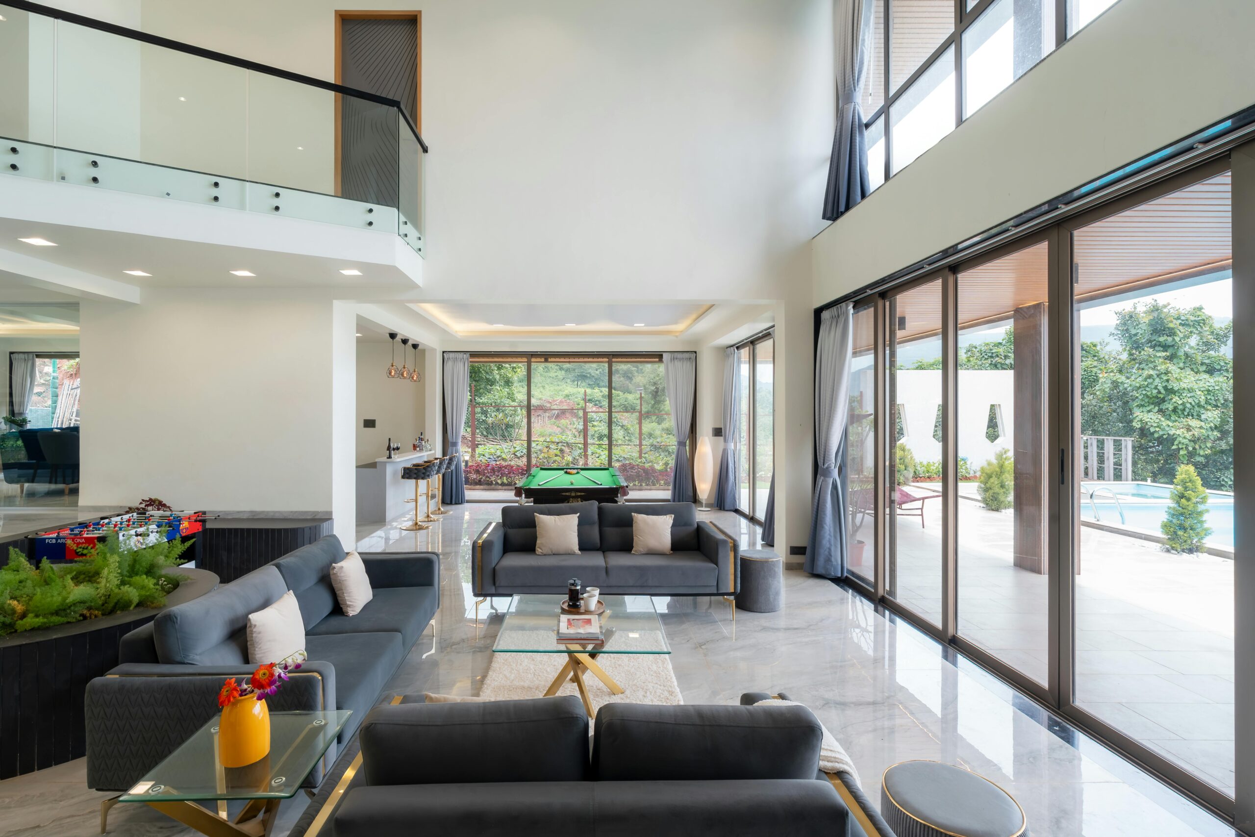 Spacious modern living room with glass walls, open view to pool and garden.