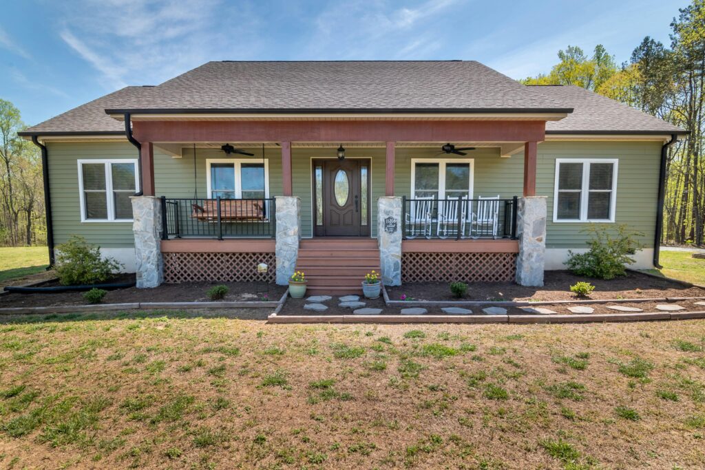 A cozy modern suburban family home with a spacious porch and landscaped yard.